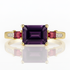 Gold ring with a purple gemstone and pink accents on a white background