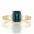 Gold ring with a blue gemstone and clear stones on a white background