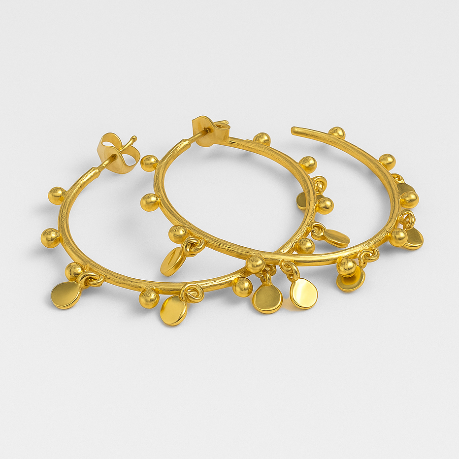 Gold hoop earrings with small round embellishments on a light grey background