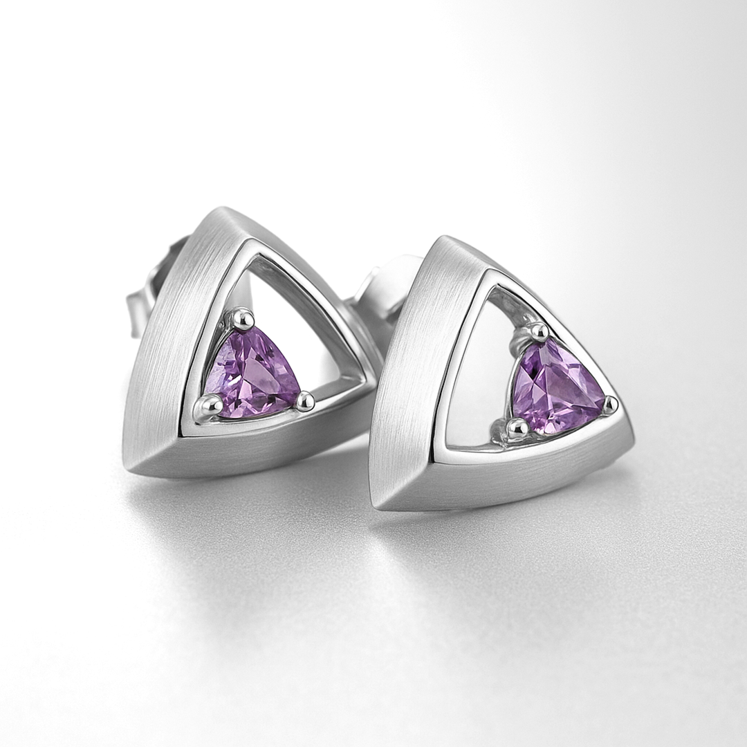Pair of silver earrings with purple gemstones on a white background