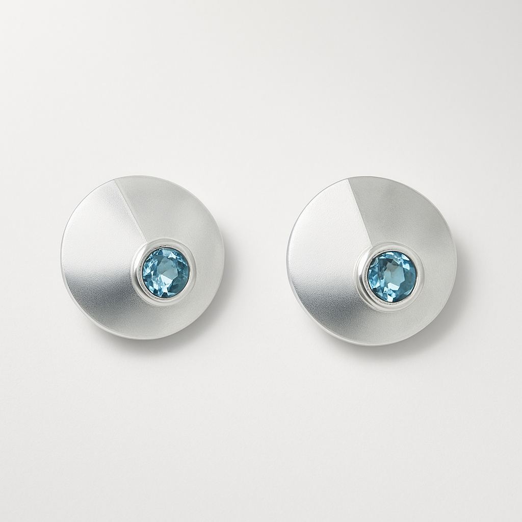 Pair of silver earrings with blue gemstones on a light gray background