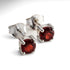 Silver stud earrings with red gemstones on a white background