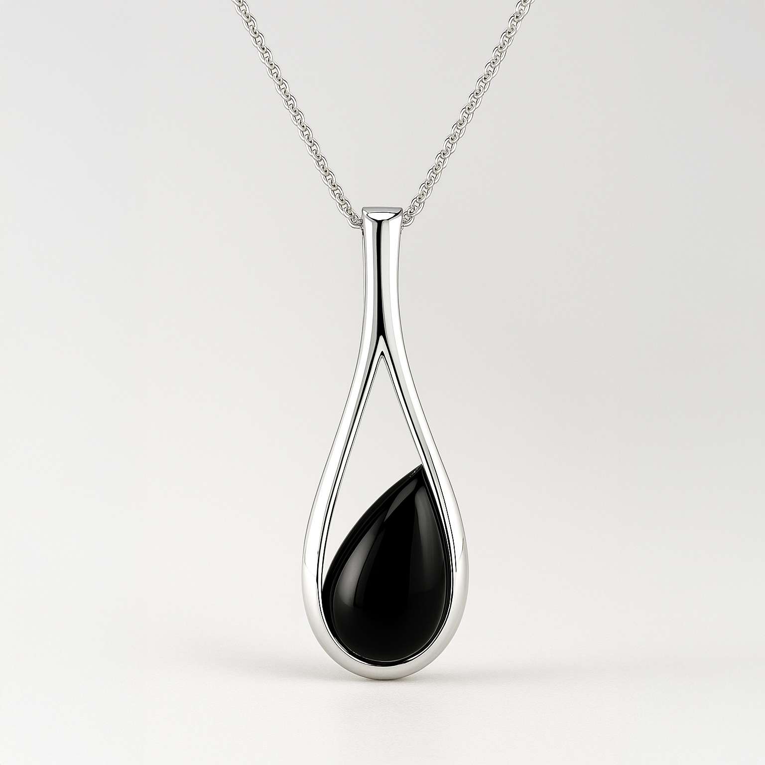 Silver pendant with a black teardrop-shaped stone on a white background