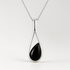 Silver pendant with a black teardrop-shaped stone on a white background