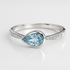 Silver ring with a pear-shaped blue gemstone on a light gray background