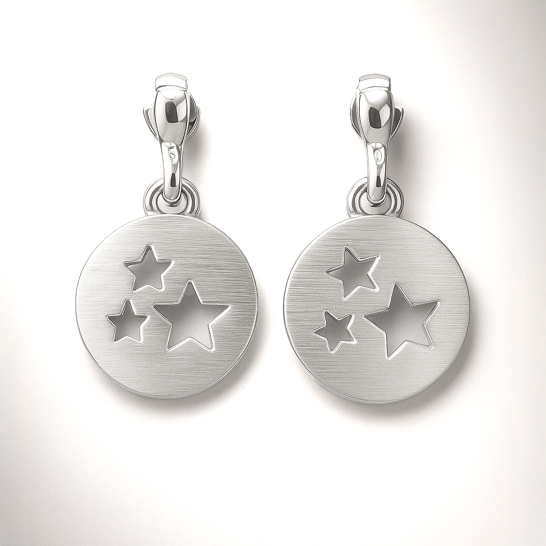Pair of silver pendants with star designs on a white background